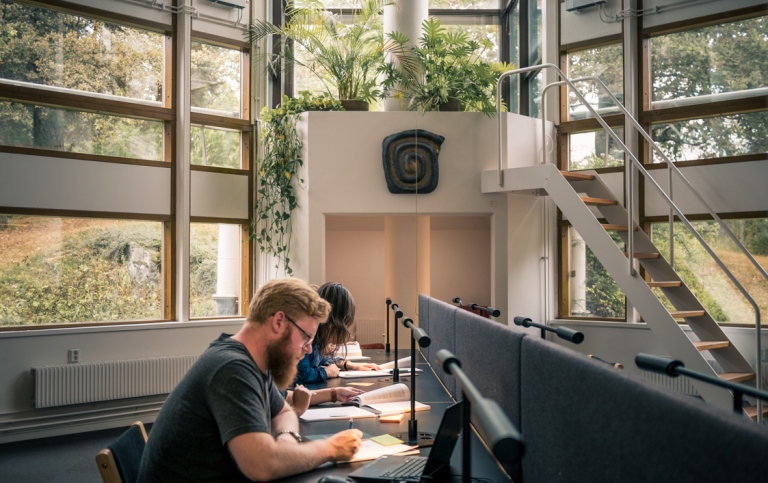 Studenter pluggar vid skrivbord i biblioteket